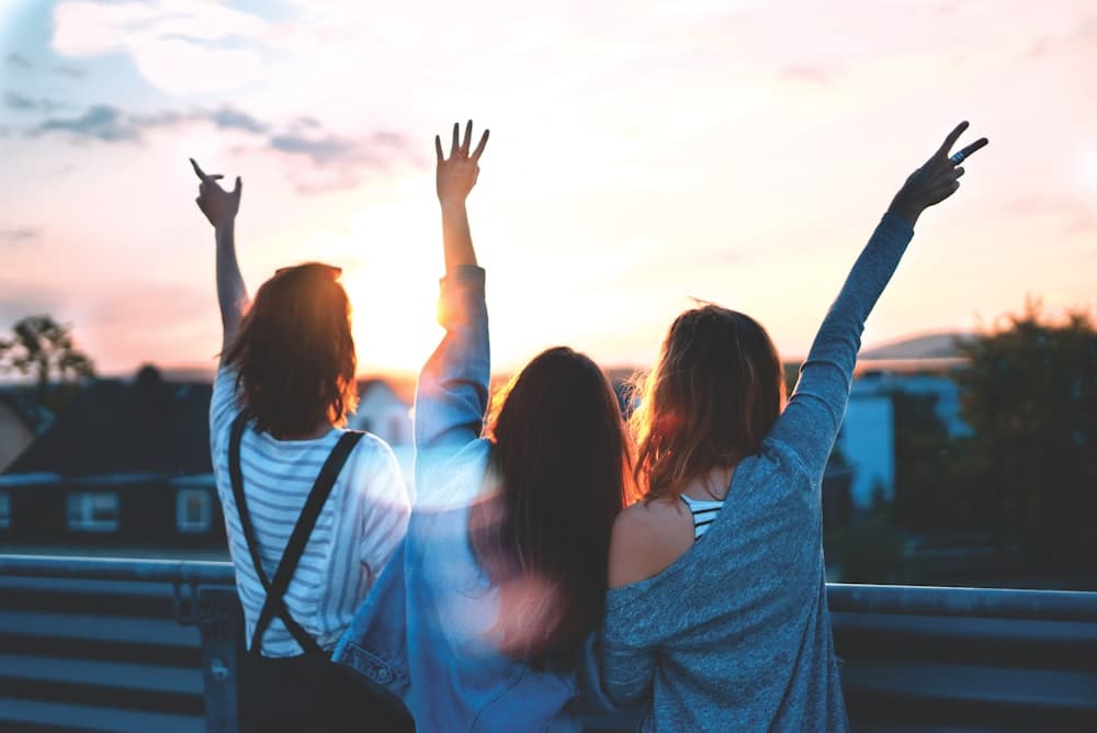 Friends celebrating at sunset with hands raised